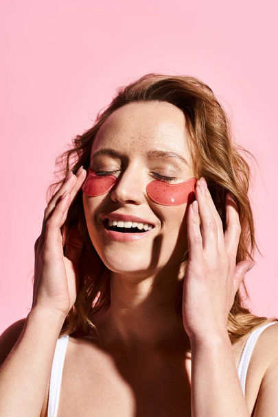 Женщина с розовыми повязками на лице, олицетворяющая уход за собой и расслабление. - Фото, изображение