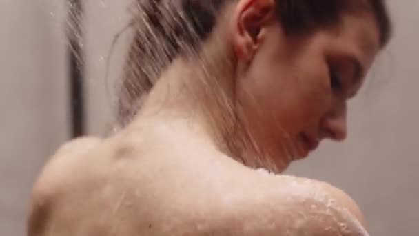 Молода жінка стоїть під душем і змиває піну. Брюнетка приймає теплий душ перед сном. Високоякісні FullHD кадри
 - Кадри, відео