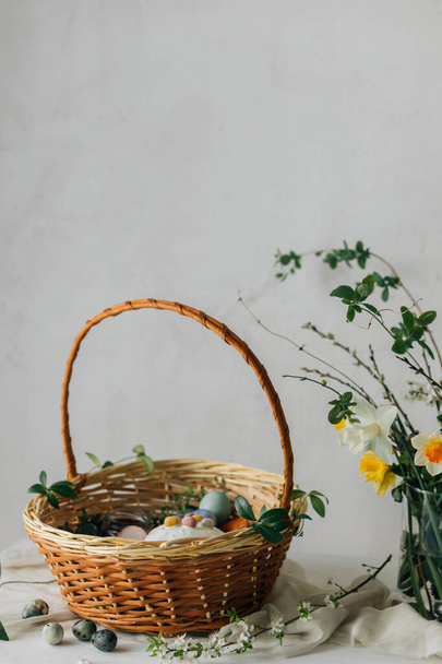 Stijlvolle paasmand met eieren en voedsel met lentebloemen op rustieke tafel. Vrolijk Pasen! Traditioneel paasvakantie eten. Moderne natuurlijke kleurstof eieren, lekkere ham, brood, boter, bieten - Foto, afbeelding