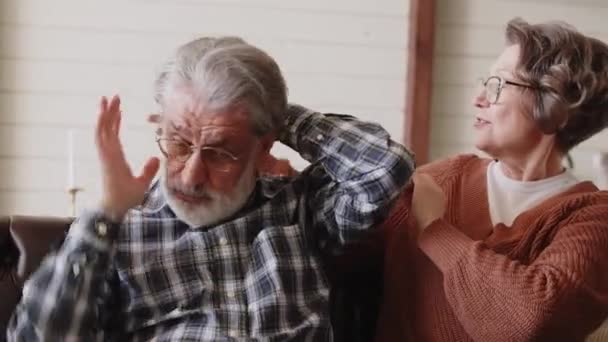 Μια ηλικιωμένη σύζυγος ισιώνει τα γκρίζα μαλλιά του άντρα της και γελάει. Δείχνοντας φροντίδα και αγάπη. Υψηλής ποιότητας 4k πλάνα - Πλάνα, βίντεο
