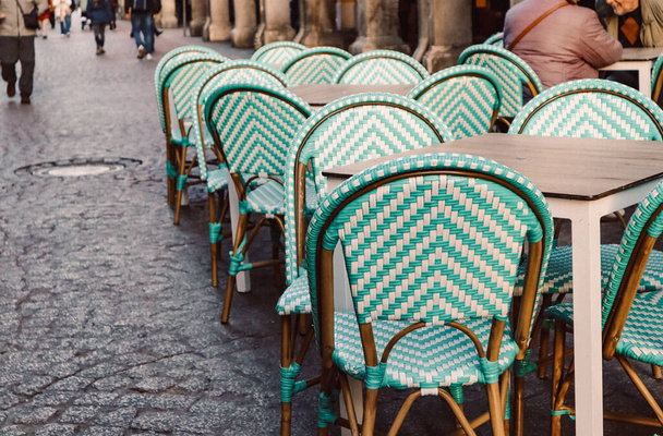 Blassgrüne Stühle im Café, Restaurantterrasse. Leere Sitze, Tische auf der Altstadtstraße. Möbel im Freien. Menschen gehen. Romantischer Ort. - Foto, Bild