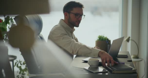 Πλευρική άποψη του επιχειρηματία μαζεύοντας ημερολόγιο, ενώ εργάζονται σε φορητό υπολογιστή κάθεται στο γραφείο στο γραφείο - Πλάνα, βίντεο