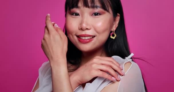 化粧品,ピンクのバックグラウンド,日本のために幸せなスキンケアメイクのスタジオで女性,アジアと顔. 女性,笑顔,肖像画,手触りで自信,治療,モックアップスペース. - 映像、動画