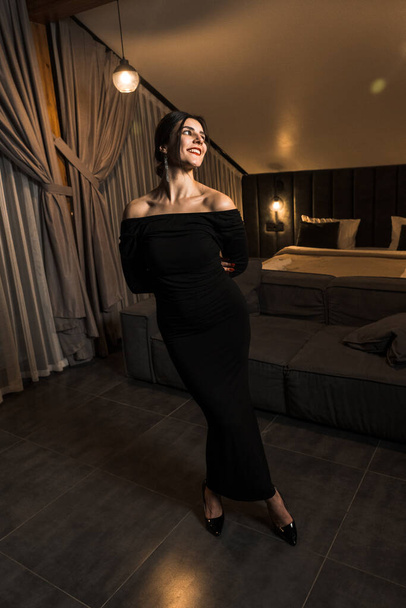 Mulher elegante em um vestido preto posando em um apartamento. Conceito de tiro moda - Foto, Imagem