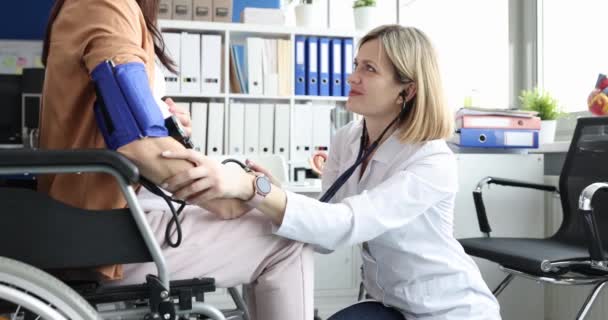 Doctor checks blood pressure of pregnant woman in wheelchair. Gynecologist and medical control of pregnant women with disabilities concept - Felvétel, videó