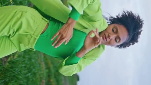 Mulher coreógrafa dançando ao ar livre no campo nublado. Africano americano inspirado dançarino menina realizando dança contemporânea em grama verde tiro vertical. Artista sensual corpo em movimento suavemente na natureza - Filmagem, Vídeo