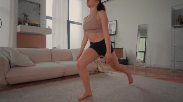 joven morena practicando yoga indoor cámara lenta mujer haciendo ejercicios fitness en apartamento - Imágenes, Vídeo