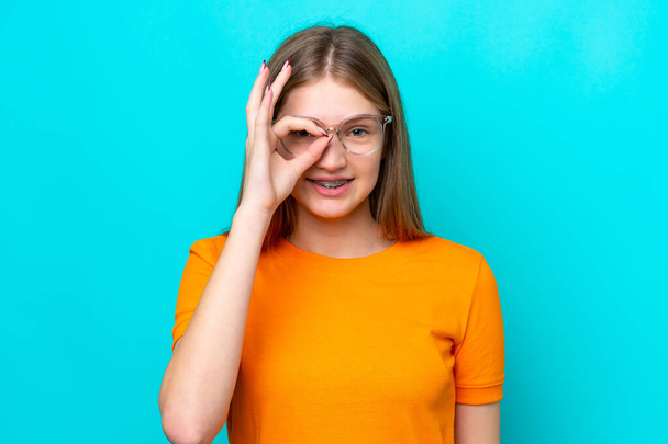 Tini orosz lány elszigetelt kék háttér szemüveggel boldog arckifejezéssel - Fotó, kép