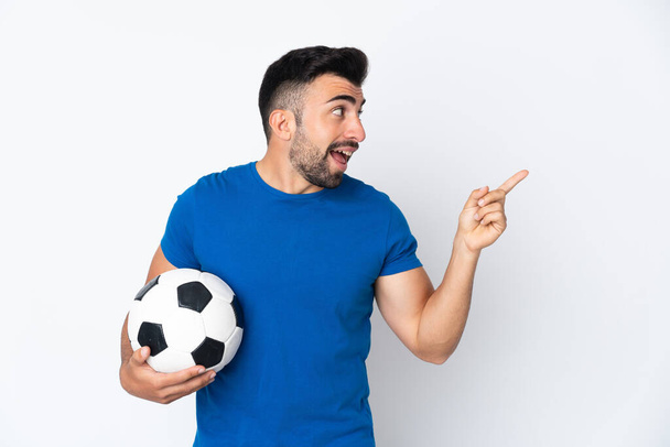 Guapo joven jugador de fútbol hombre sobre la pared aislada con la intención de darse cuenta de la solución mientras levanta un dedo - Foto, Imagen