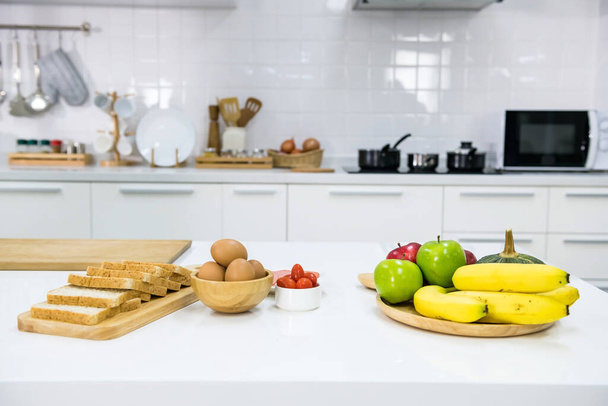 Szendvics készítés a konyhában reggelire. Teljes kiőrlésű kenyér, tojás, paradicsom, zöldség és gyümölcs. Egészséges táplálkozás. - Fotó, kép