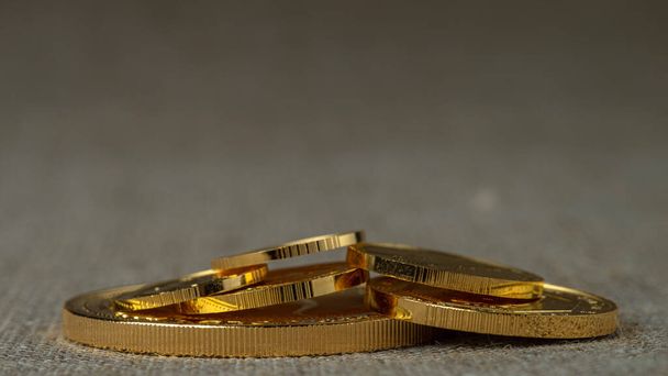 A pile of gold coins of various sizes on a neutral blurred background. Selective focus. - Photo, Image