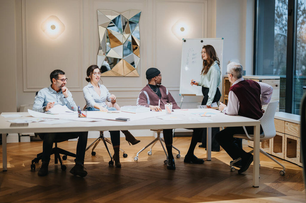 Multigenerationeel team van zakelijke professionals bespreekt samen strategieën in een goed verlichte hedendaagse kantooromgeving. - Foto, afbeelding