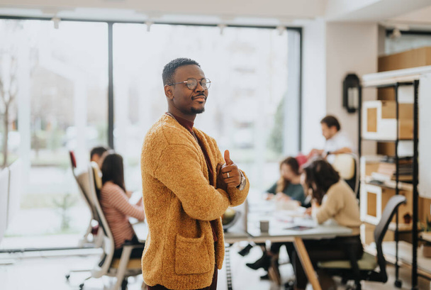 Αυτοπεποίθηση Αφροαμερικανός επιχειρηματίας δίνει αντίχειρες σε ένα πολυάσχολο σύγχρονο γραφείο. - Φωτογραφία, εικόνα
