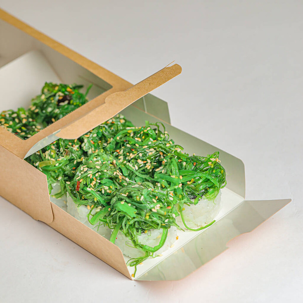 Картонна коробка, наповнена різними зеленими овочами, розміщеними на столі. - Фото, зображення