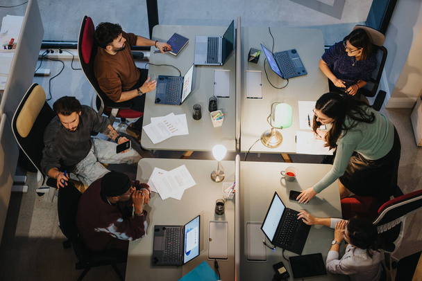 Vue aérienne d'un groupe multigénérationnel diversifié de professionnels discutant dans un environnement de bureau, mettant en valeur le travail d'équipe et la collaboration. - Photo, image