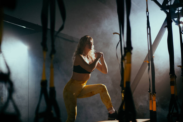 Jeune femme blonde avec formation de cheveux bouclés dans la salle de gym - Photo, image