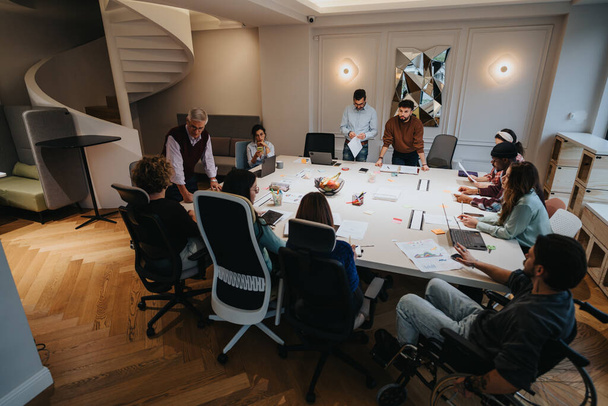 A soknemzetiségű szakemberek egy élénk üzleti találkozón vesznek részt egy kreatív légkörrel rendelkező, kortárs munkahelyen. - Fotó, kép