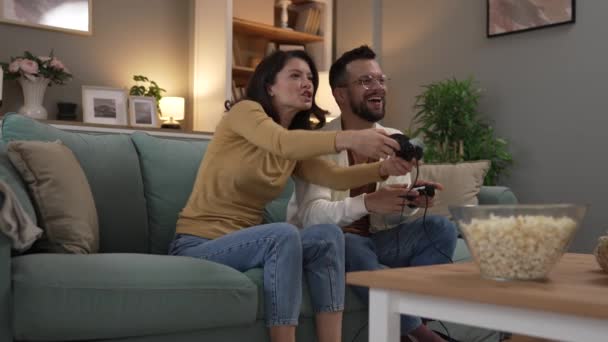 Adult couple man and woman caucasian husband and wife or boyfriend and girlfriend play console video games at home hold joystick controller have fun leisure joy and bonding concept - Footage, Video