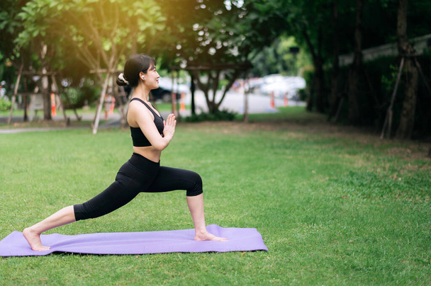 Pembe spor giyim giymiş genç Asyalı bir kadının portresi. Parkta kasları germek. Yoga ve egzersizle sağlığınızı ve güzelliğinizi arttırın. Açık hava egzersizlerinin arasında iç ahengi keşfet.. - Fotoğraf, Görsel