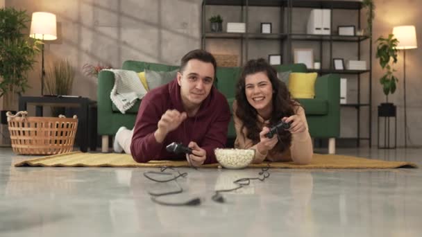 Felnőtt pár férfi és nő kaukázusi férj és feleség vagy barát és barátnő játszani konzol videojátékok otthon hold joystick vezérlő szórakozás szabadidő öröm és kötődés koncepció - Felvétel, videó