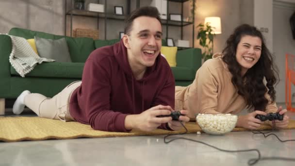 Felnőtt pár férfi és nő kaukázusi férj és feleség vagy barát és barátnő játszani konzol videojátékok otthon hold joystick vezérlő szórakozás szabadidő öröm és kötődés koncepció - Felvétel, videó