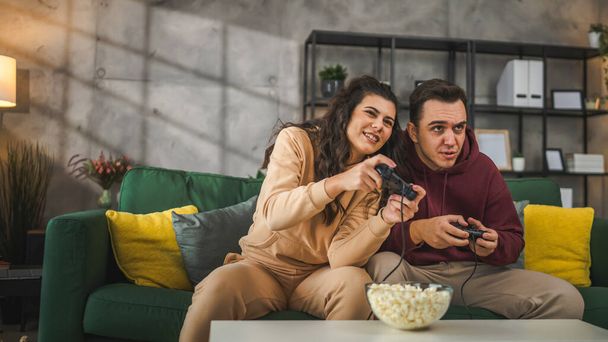 Dospělí pár muž a žena kavkazský manžel a manželka nebo přítel a přítelkyně hrát konzole videohry doma držet joystick regulátor bavit volný čas radost a bonding koncept - Fotografie, Obrázek