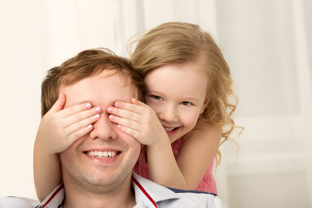 Tochter spielt mit Vater, der die Augen schließt - Foto, Bild