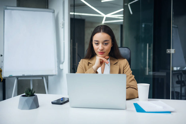 Una donna d'affari attraente seduto di fronte al computer portatile e la gestione della sua attività da ufficio. - Foto, immagini