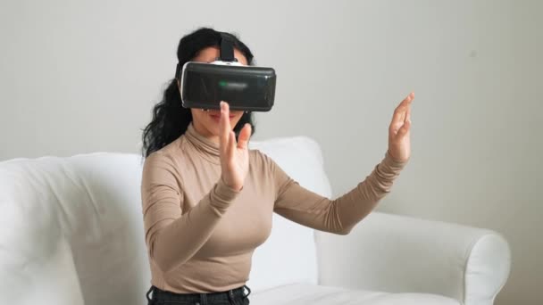 Νεαρή γυναίκα που χρησιμοποιεί εικονική πραγματικότητα VR goggle στο σπίτι για κρίσιμη εμπειρία online αγορών. Η καινοτομία εικονικής πραγματικότητας VR βελτιστοποιημένη για τον γυναικείο τρόπο ζωής ψηφιακής ψυχαγωγίας. - Πλάνα, βίντεο