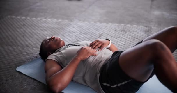 Tired, exercise and black man on the floor, gym and fatigue with workout or progress with hobby. Exhausted, wellness center or African person relax after intense training or health goals with fitness. - Footage, Video