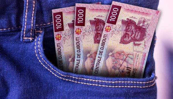 Ένα μάτσο χαρτονομίσματα των 1000 φράγκων του Τζιμπουτί σε μια τσέπη τζιν. - Φωτογραφία, εικόνα