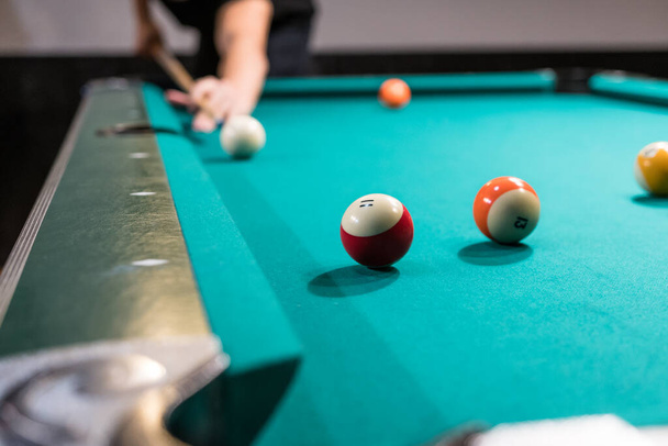 Pool table billiard game with shallow depth of field. Hand holding a pool cue taking a shot - Photo, Image