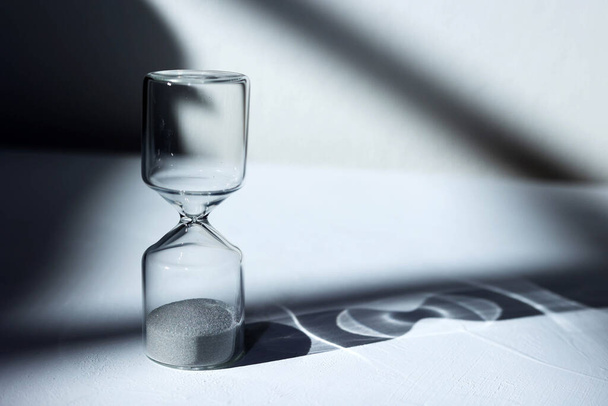 Hourglass on the desk Striking light, shadow and glass reflections - Photo, Image