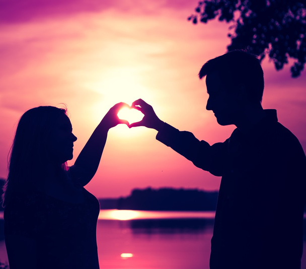 Paar doen hart vorm met hun handen op het meer kust.  - Foto, afbeelding