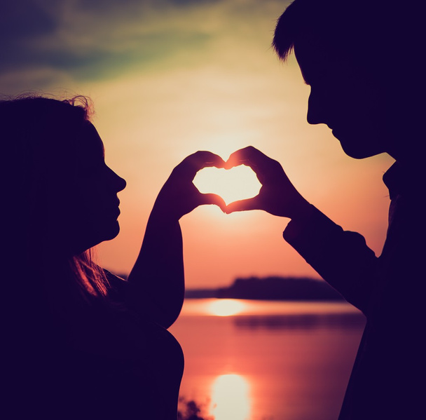 Пара в форме сердца с руками на берегу озера.  - Фото, изображение