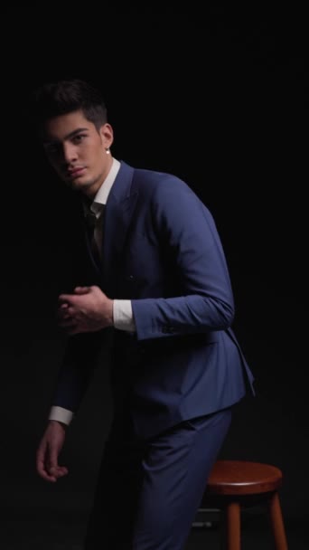 sexy junger Geschäftsmann geht, sitzt auf Stuhl, passt blauen Anzug an, faltet die Arme, berührt Kinn und denkt - Filmmaterial, Video
