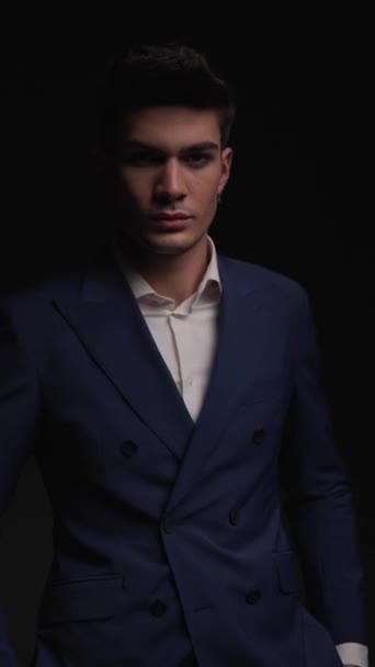 eleganter Modemann im blauen Anzug, die Hände in den Taschen, zur Seite schauend und arrogant, während er Kinn und Denken berührt - Filmmaterial, Video