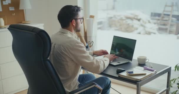 Fiatal üzletember ül a széken, és dolgozik laptop íróasztal az irodában - Felvétel, videó