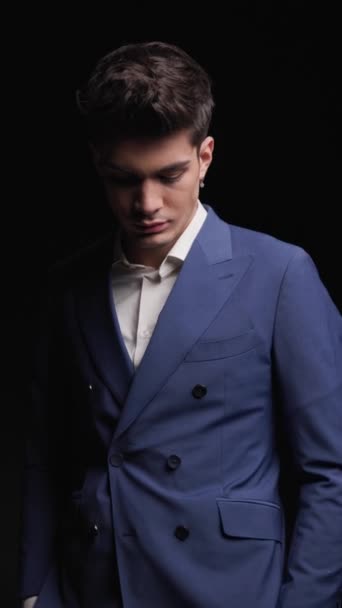 таинственный модный человек в синем костюме, смотрящий вниз, держащий руки в карманах и уходящий в темноте - Кадры, видео