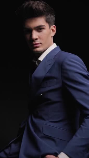 closeup of young fashion man wearing double breasted blue suit looking down to side on black background - Footage, Video