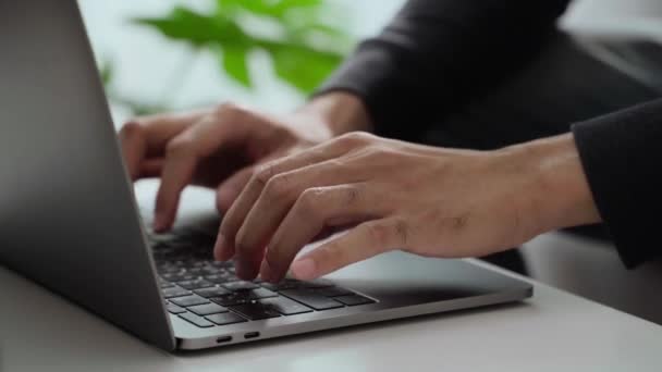 De hand van de man typt op een laptop toetsenbord thuis of op kantoor. Hij werkt, verstuurt berichten, chat, surft op het internet en gebruikt sociale netwerken. - Video