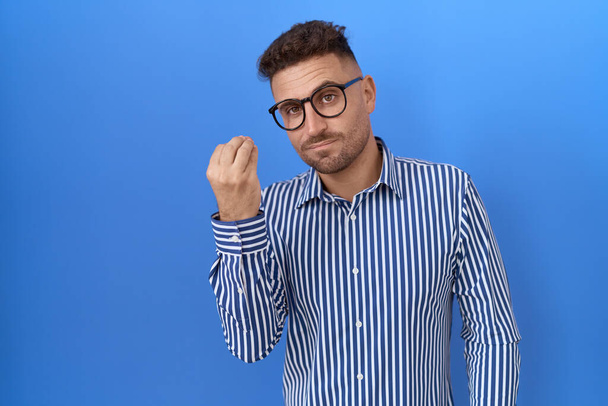 Homme hispanique avec barbe portant des lunettes faisant geste italien avec la main et les doigts expression confiante  - Photo, image