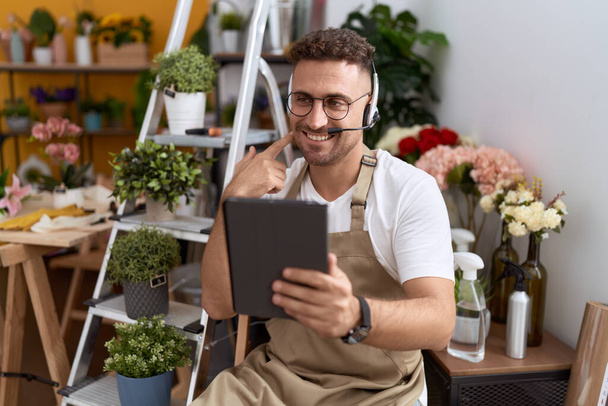 Hispanic man with beard working at florist shop doing video call smiling happy pointing with hand and finger  - Foto, Imagen