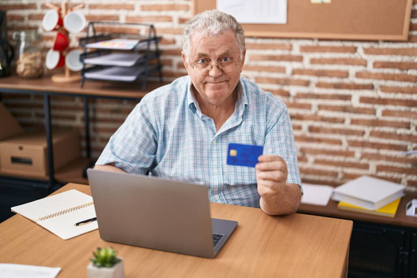 オフィスでノートパソコンやクレジットカードを使用している中世の白髪ビジネスワーカー - 写真・画像