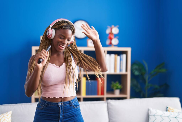 Femme afro-américaine écoutant de la musique chanter à la maison - Photo, image