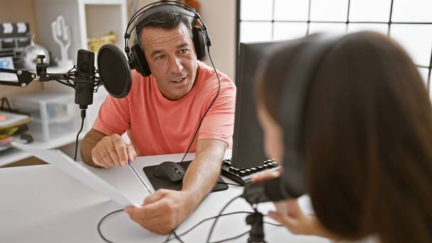 Am Sendepuls unterhalten sich Mann und Frau im Radio, lesen gemeinsam Zeitung im lebendigen Radiostudio - Foto, Bild