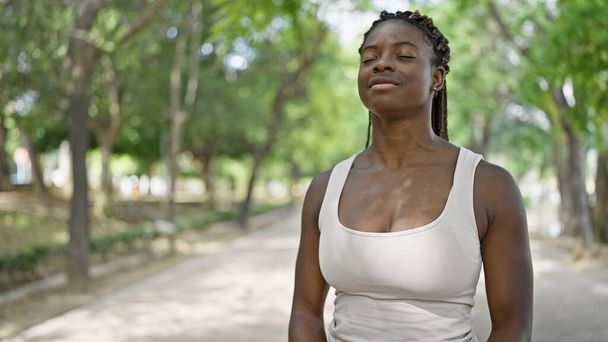 Mujer afroamericana sonriendo confiada respirando en el parque - Foto, Imagen