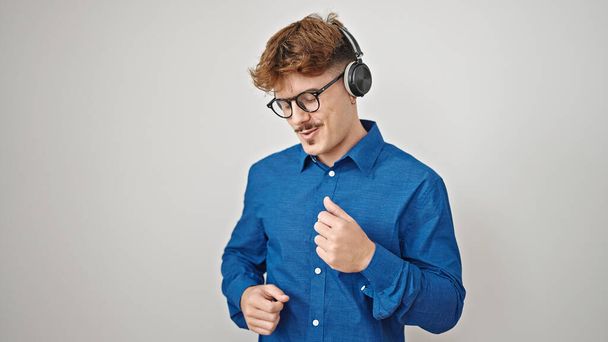 Fiatal spanyol férfi hallgat zenét és táncol elszigetelt fehér háttér - Fotó, kép