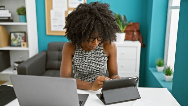 Trabajadora de negocios afroamericana usando touchpad y laptop en la oficina - Foto, Imagen