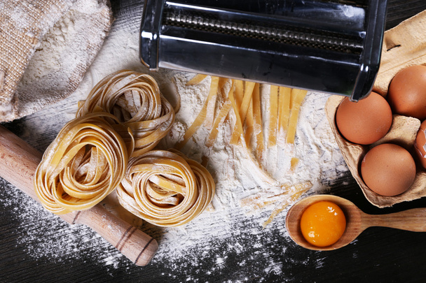 Metal pasta maker machine and ingredients for pasta on wooden background - Foto, Bild